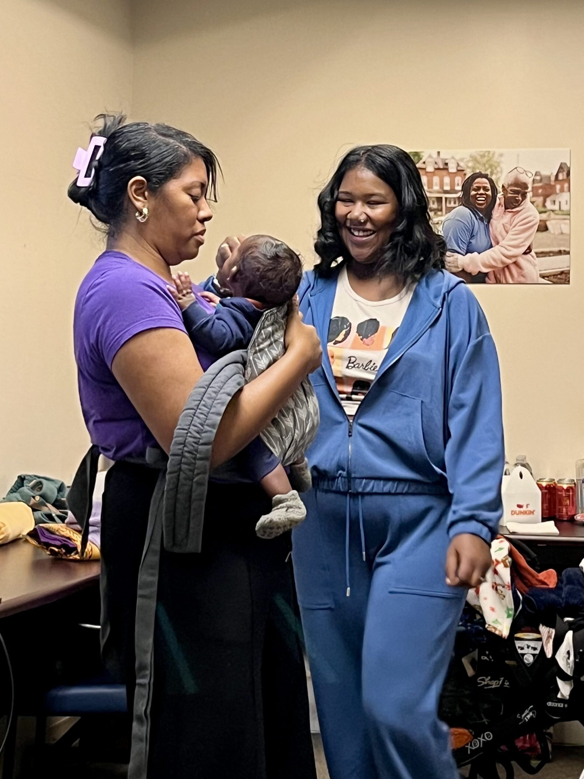 Supporting a new mom and doula with babywearing with her newborn.